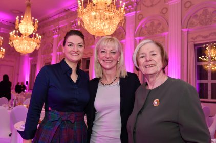 Digitalministerin Judith Gerlach mit Staatssekretärin Carolina Trautner und Prof. Ursula Männle in einem pink erleuchteten Saal mit Kronleuchtern.