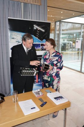 Preisträger Prof. Dr. Klaus Schilling, Zentrum für Telematik Würzburg (links), erläutert Digitalministerin Judith Gerlach, MdL (rechts), das Projekt CloudCT und die entwickelten Mini-Satelliten.