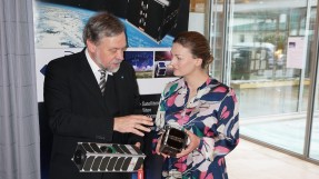 Digitalministerin Judith Gerlach steht neben Prof. Schilling, beide halten Mini-Satelliten in der Hand