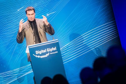 Ministerpraesident Dr. Markus Soeder steht an einem blauen Rednerpult mit der Aufschrift 'Digital Gipfel Nürnberg 2018' und spricht
