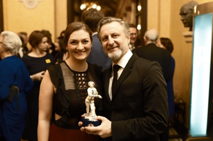 Digitalministerin Judith Gerlach, MdL, und Robert Marciniak beim Bayerischen Fernsehpreis. Marciniak haelt seine Preisfigur in die Kamera.Digitalministerin Judith Gerlach, MdL, und Robert Marciniak beim Bayerischen Fernsehpreis. Martínez hält seine Preisfigur in die Kamera.