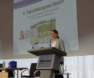 Digitalministerin Judith Gerlach, MdL, steht am Rednerpult und haelt eine Keynote beim 5. Zukunftskongress Bayern des Behoerden Spiegels. Hinter ihr ist der Schriftzug 5. Zukunftskongress Bayern zu lesen.