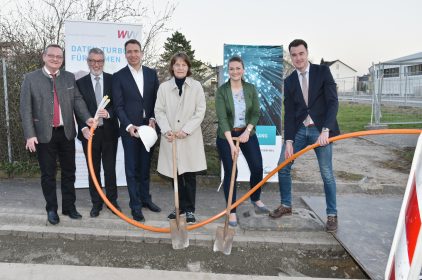 Gruppenbild mit Digitalministerin Judith Gerlach, MdL, Manfred Ländner, MdL, WVV-Geschäftsführer Thomas Schäfer, Dr. Andreas Jahn,COO der iWelt AG, Christina Held und Markus Schenk, dem Vorsitzenden der Verwaltungsgemeinschaft Eibelstadt beim Spatenstich. Die beiden Damen haben jeweils einen Spaten in der Hand, während die Herren im Bild ein oranges Kabel halten.