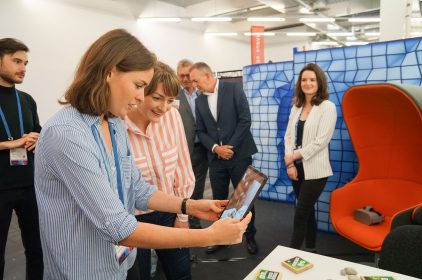 Leas Weil vom Leibniz-Rechenzentrum hält ein Tablet in der Hand. Digitalministerin Gerlach blickt darauf und lächelt.