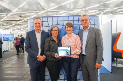 Digitalministerin Judith Gerlach, MdL, mit Stefan Sutor, dem Geschäftsführer der Medientage München, Silke Schmidt, der Leiterin des XR HUB Bavaria/Munich, Siegfried Schneider, dem Präsidenten der Bayerischen Landeszentrale für neue Medien (v.l.n.r.) und einem Tablet mit der Aufschrift 'Förderbescheid XR HUB München'.