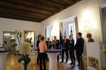 Digitalministerin Gerlach spricht mit Vertretern bayerischer Firmen in Tschechien in einem prunkvollen Saal.