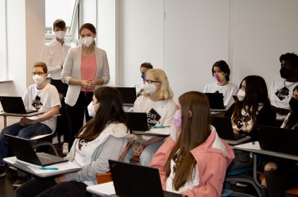 Digitalministerin Gerlach steht in einer Gruppe Schüler, die auf ihren Laptops eine Internetseite programmiert haben