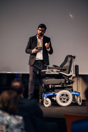 Claudiu Leverenz, Geschäftsführer von Munevo, stellt dem Publikum sein innovatives Rollstuhlsteuerungssystem mit intelligenter Brille vor.