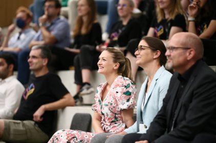 Digitalministerin Judith Gerlach sitzt inmitten des Publikums und lächelt.