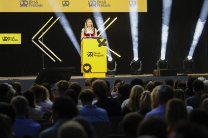 Digitalministerin Judith Gerlach spricht vor Publikum auf der Bühne der Bits & Pretzels 2023. Sie steht hinter einem gelben Rednerpult.