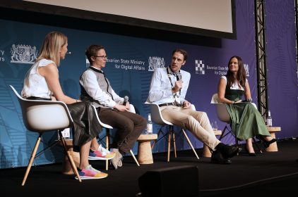 Paneldiskussion auf der Bits & Pretzels. Logo des Digitalministeriums im Hintergrund.