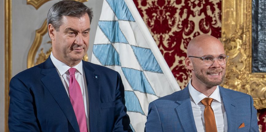 Ministerpräsident Dr. Markus Söder und Digitalminister Dr. Fabian Mehring lächelnd bei Urkundenübergabe.