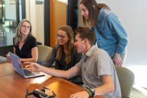 Gruppe von vier Personen vor einem Laptop