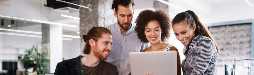 Zwei Männer und zwei Frauen, die lachend auf einen Laptop schauen