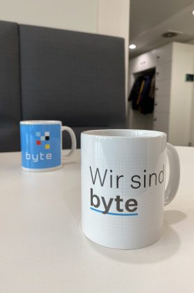 Zwei Tasse stehen auf einem Tisch. Auf der einen ist das Logo der BYTE zu sehen, auf der anderen steht die Aufschrift: Wir sind byte.