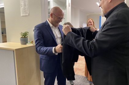 Digitalminister Dr. Fabian Mehring bekommt einen schwarzen Pullover überreicht und freut sich.